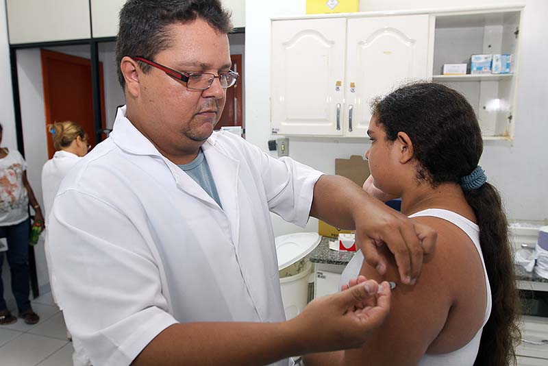 Profissional de saúde aplicando vacina em uma adolescente