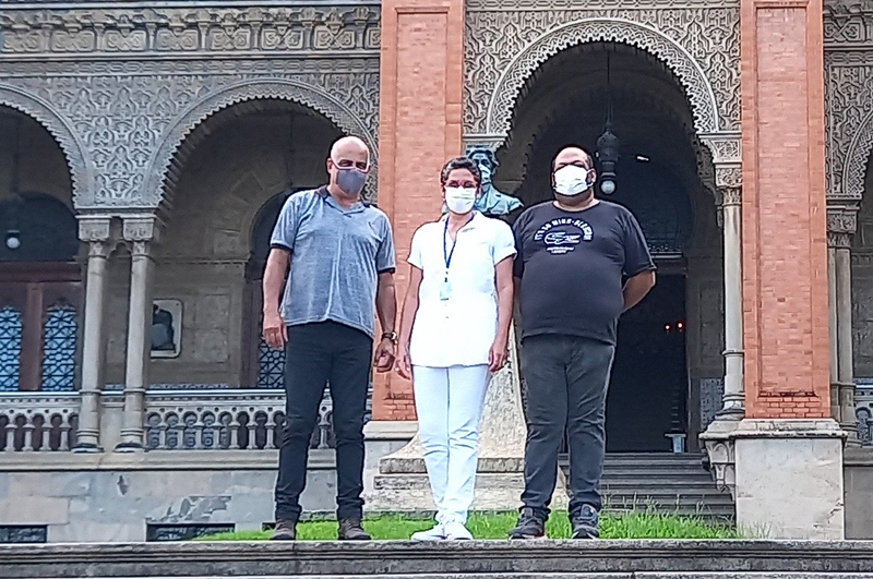 #pratodosverem #macaéacessível foto, durante o dia, na qual vemos três profissionais (um homem e duas mulheres) em frente ao prédio da Fiocruz.