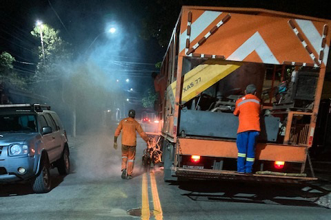 #pratodosverem #macaéacessível foto, em uma via pública à noite, na qual vemos um profissional da Secretaria de Mobilidade Urbana, uniformizado e um caminhão fazendo a sinalização horizontal  no chão.